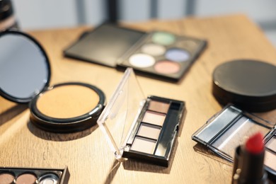 Photo of Different makeup products on wooden table indoors, closeup