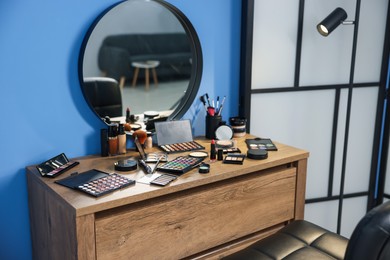 Photo of Different makeup products and brushes on vanity indoors