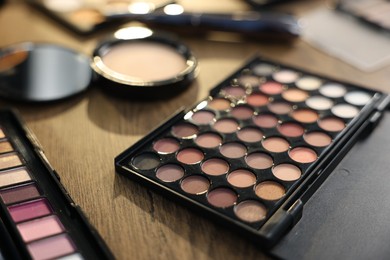 Photo of Different makeup products on wooden table, closeup
