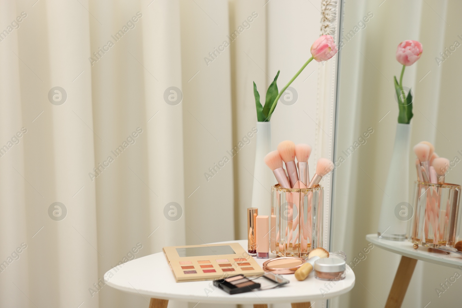 Different makeup products and brushes on white table near mirror indoors. Space for text Photo of Different makeup products and brushes on white table near mirror indoors. Space for text