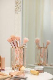 Photo of Different makeup products and brushes on white table indoors, closeup. Space for text