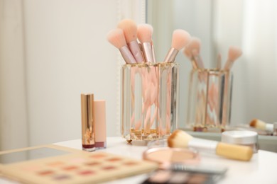 Photo of Different makeup products and brushes on white table indoors, closeup