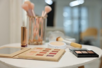 Photo of Different makeup products and brushes on white table indoors, closeup