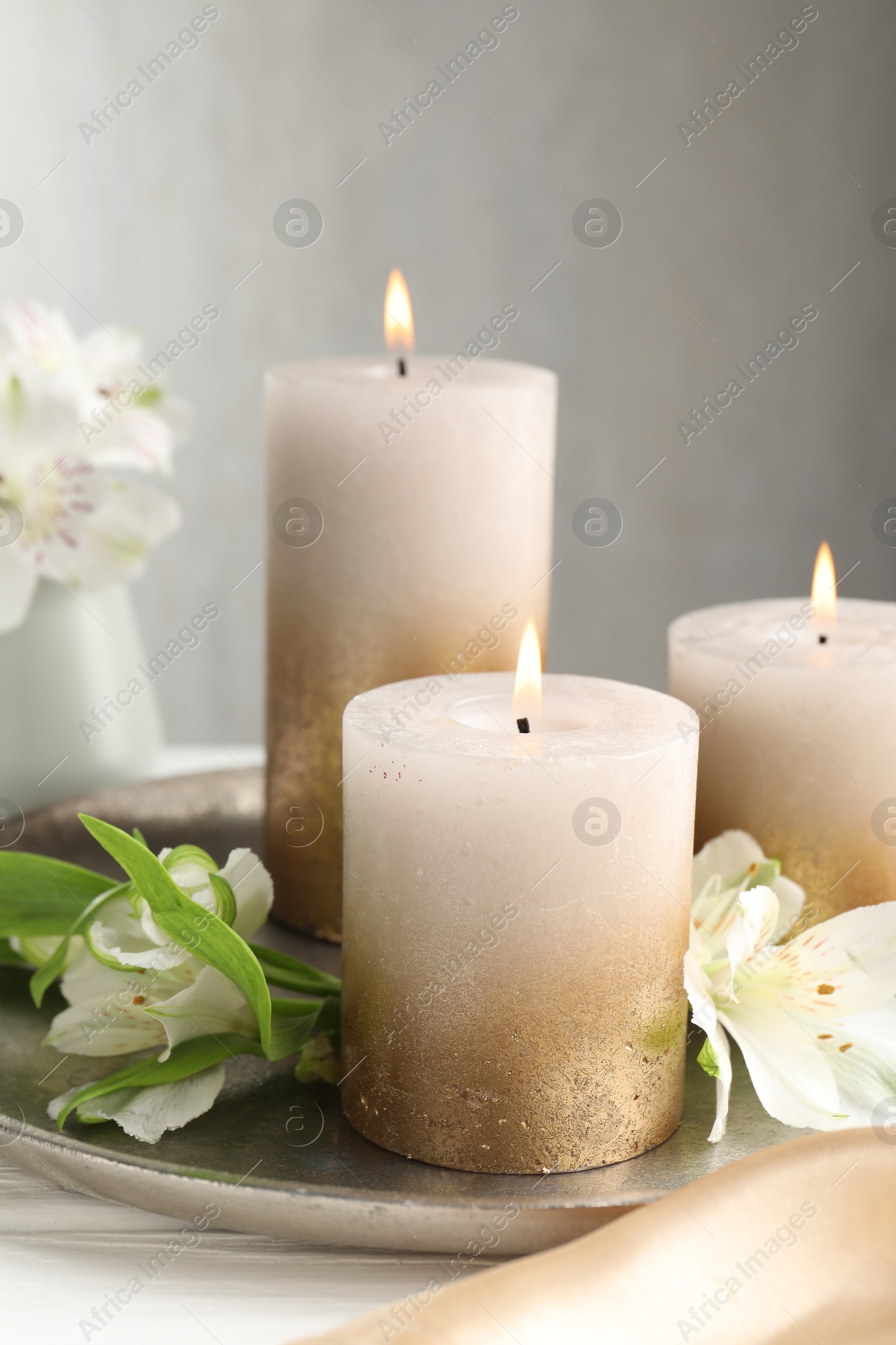 Burning candles and beautiful flowers on white table, closeup Photo of Burning candles and beautiful flowers on white table, closeup
