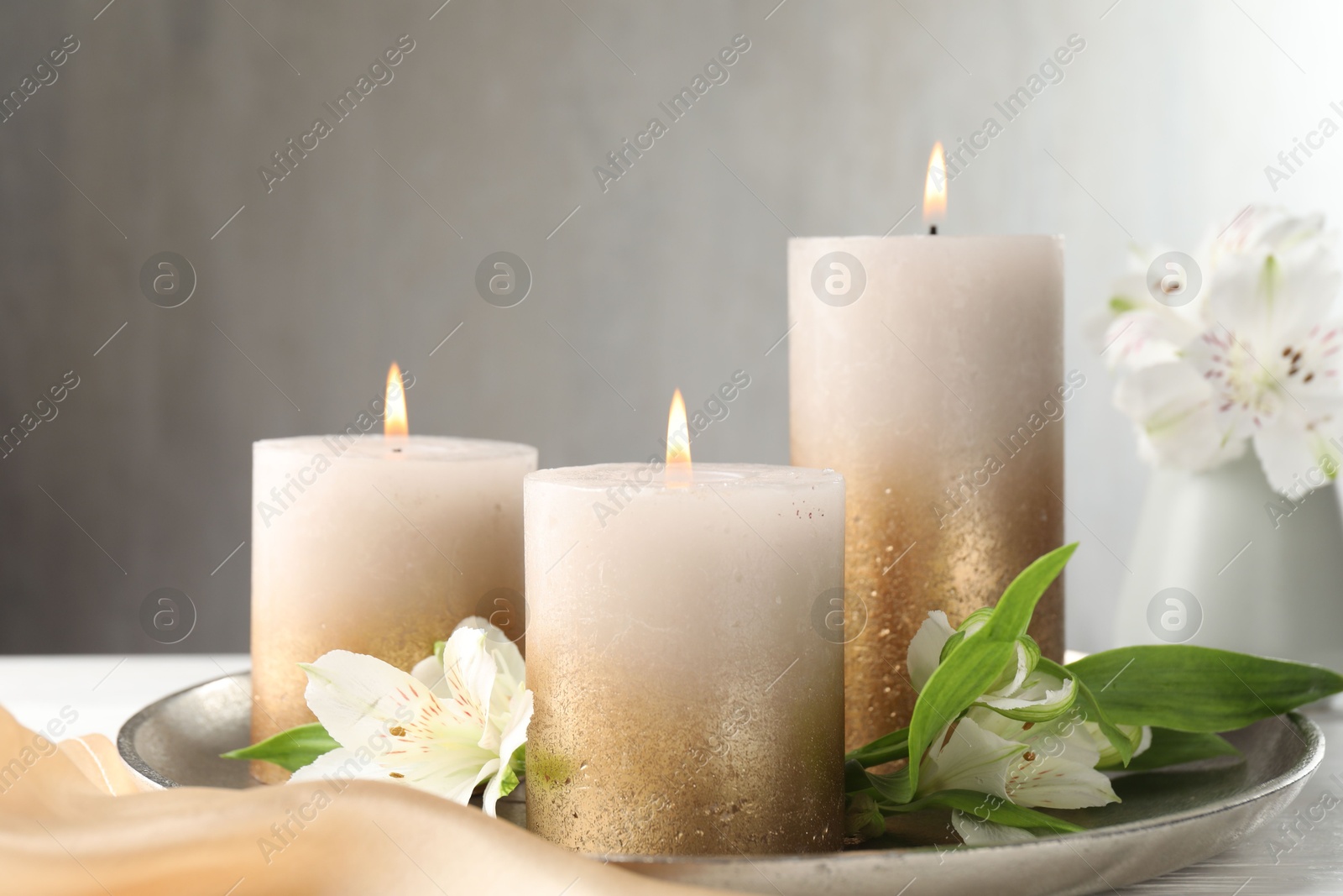 Burning candles and beautiful flowers on white table. Space for text Photo of Burning candles and beautiful flowers on white table. Space for text