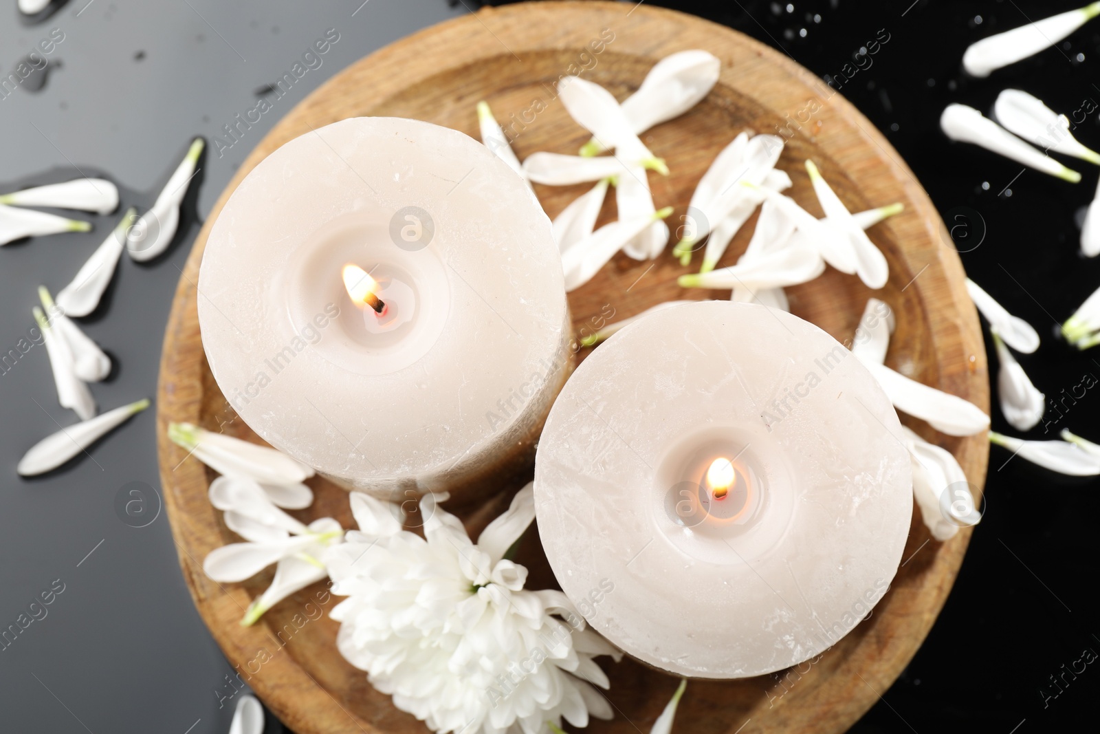 Burning candles and beautiful flowers on black table, flat lay Photo of Burning candles and beautiful flowers on black table, flat lay