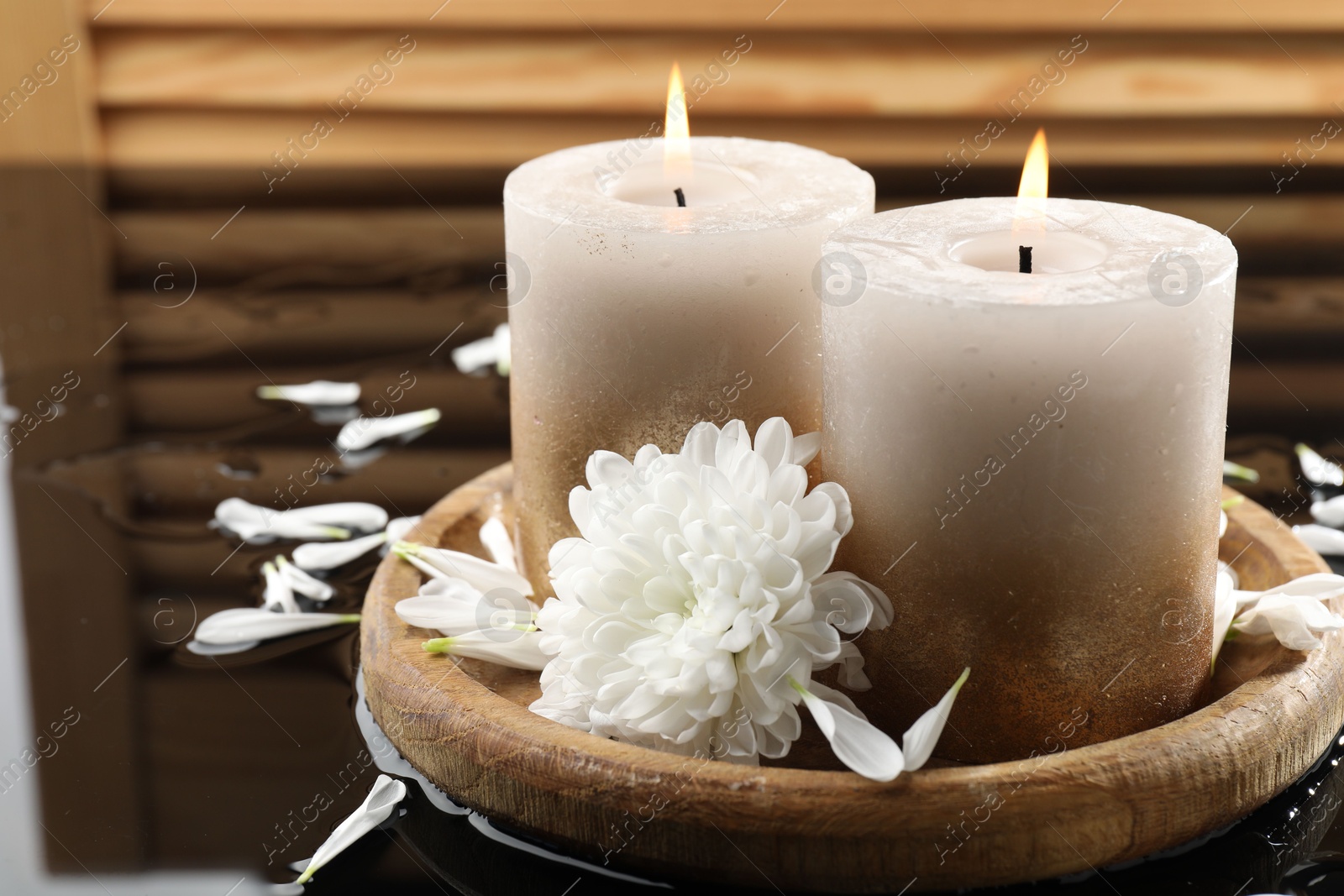 Burning candles and beautiful flowers on wet black mirror surface, closeup Photo of Burning candles and beautiful flowers on wet black mirror surface, closeup