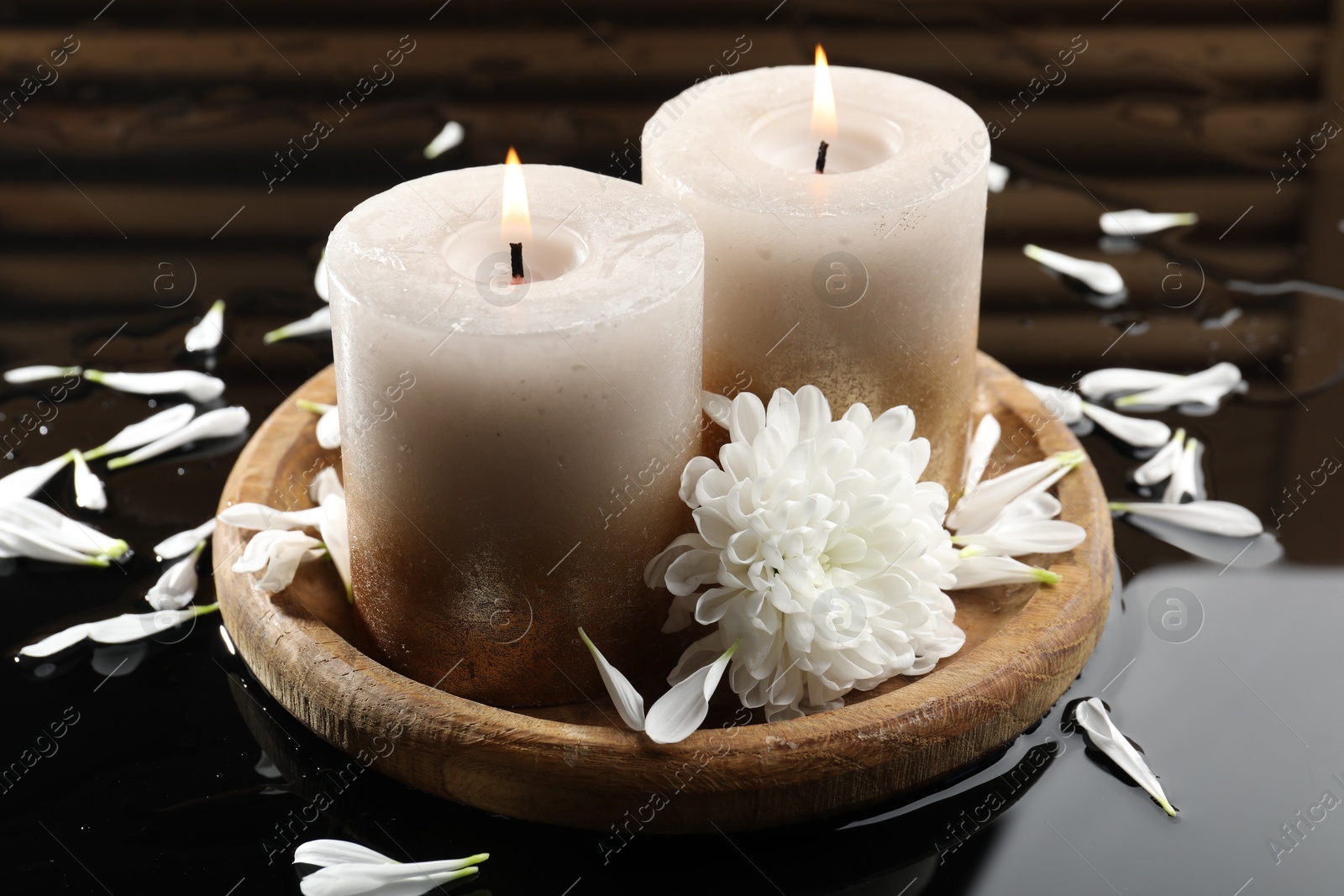 Burning candles and beautiful flowers on wet black mirror surface, closeup Photo of Burning candles and beautiful flowers on wet black mirror surface, closeup