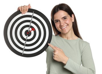 Photo of Targeting. Smiling woman pointing at dart board with arrow on white background