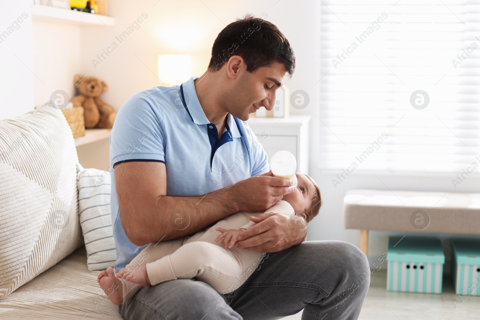 Father feeding his little baby with bottle on sofa at home Photo of Father feeding his little baby with bottle on sofa at home
