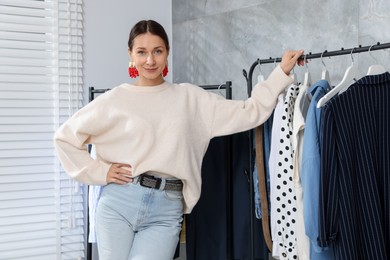 Photo of Portrait of professional stylist near clothing rack indoors