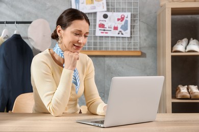 Photo of Professional stylist working on laptop at desk indoors