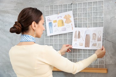 Photo of Professional stylist with pictures of outfits indoors