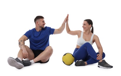 Photo of Woman and man with medicine ball giving high five on white background