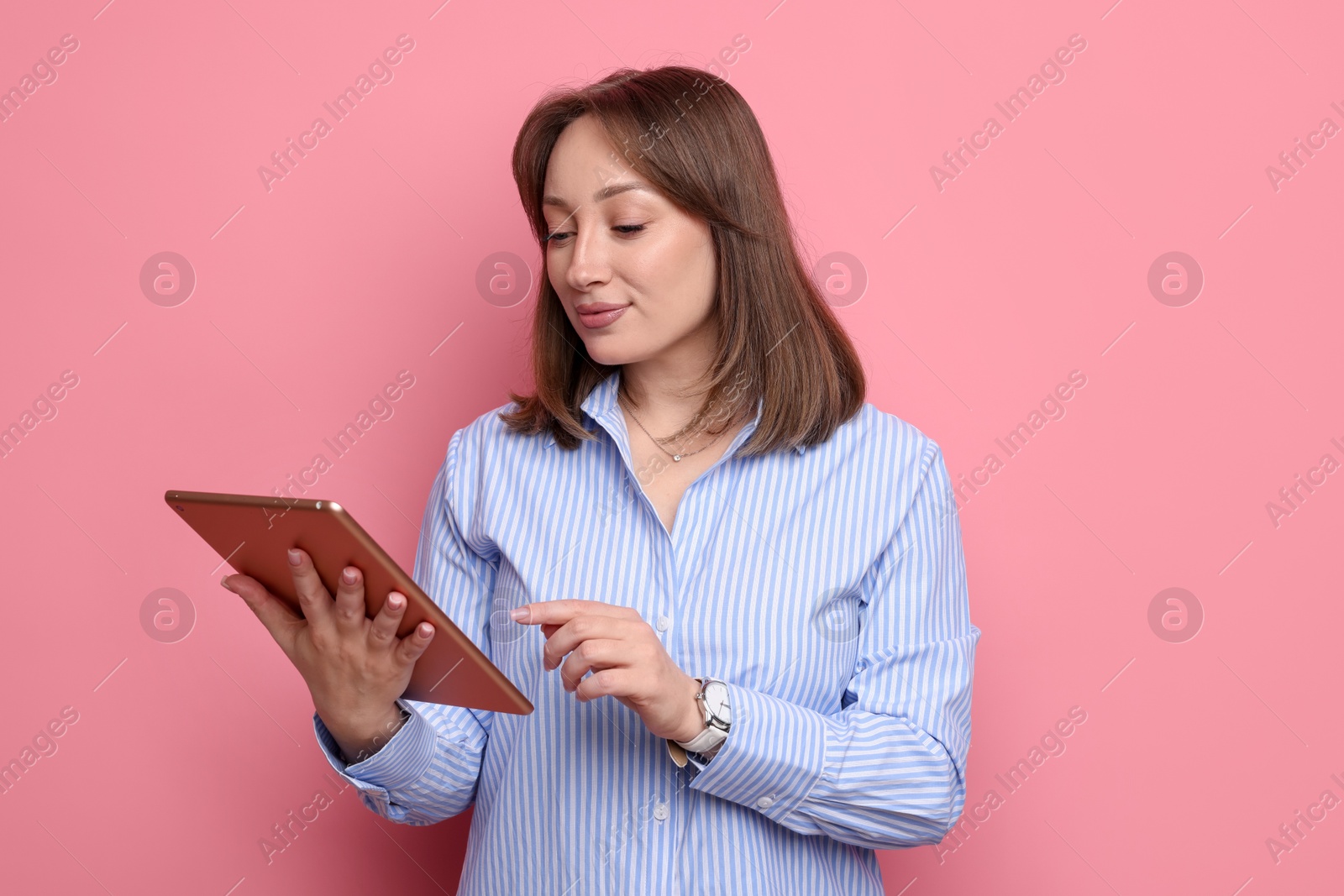 Woman with modern tablet on pink background Photo of Woman with modern tablet on pink background