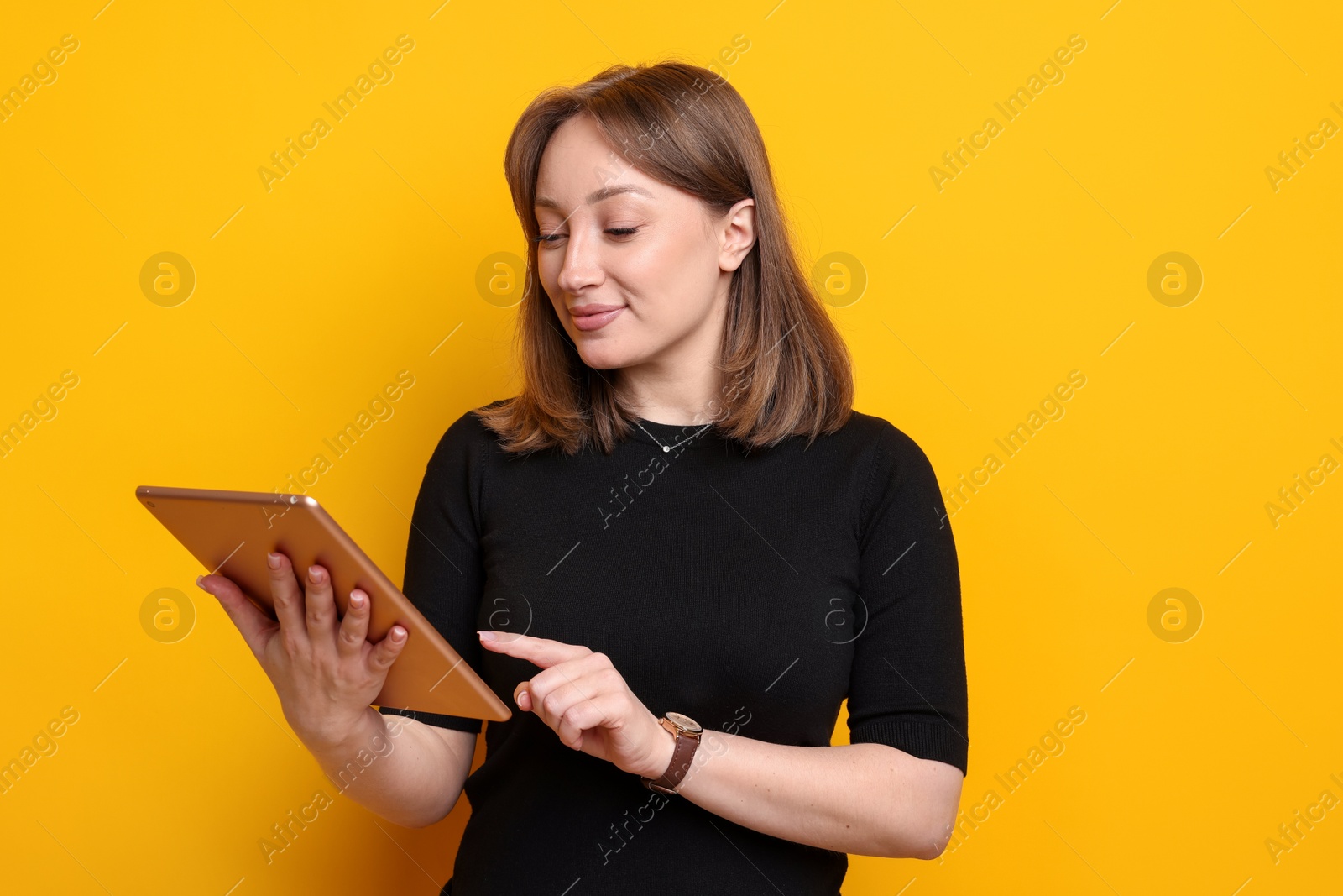 Woman with modern tablet on orange background Photo of Woman with modern tablet on orange background
