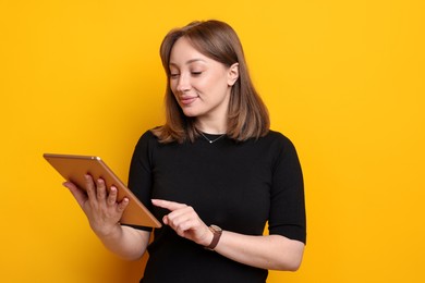 Photo of Woman with modern tablet on orange background