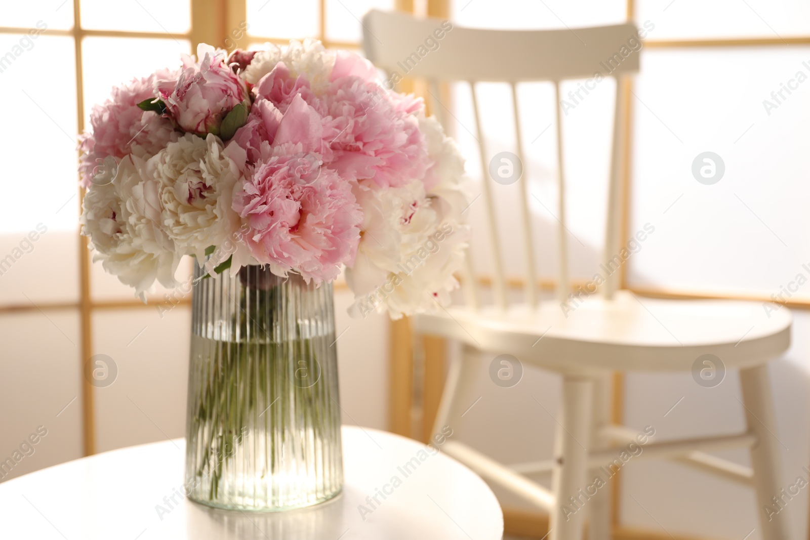 Beautiful peonies in vase on white table indoors, space for text Photo of Beautiful peonies in vase on white table indoors, space for text