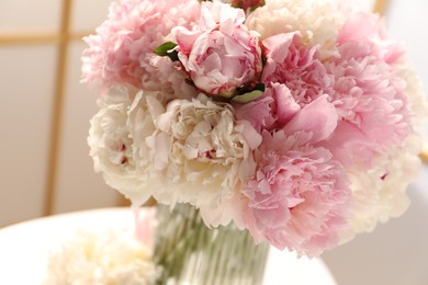 Photo of Beautiful peonies in vase on white table indoors, closeup