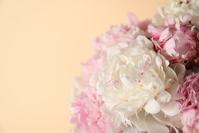 Photo of Bouquet of beautiful peonies on beige background, closeup. Space for text