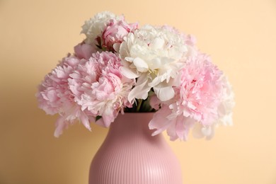 Photo of Beautiful peonies in vase on beige background, closeup