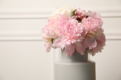 Photo of Beautiful peonies in vase near white wall, closeup