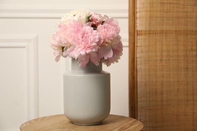Photo of Beautiful peonies in vase on wooden table indoors