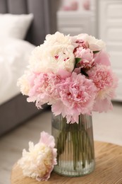 Photo of Beautiful peonies in vase on wooden table indoors