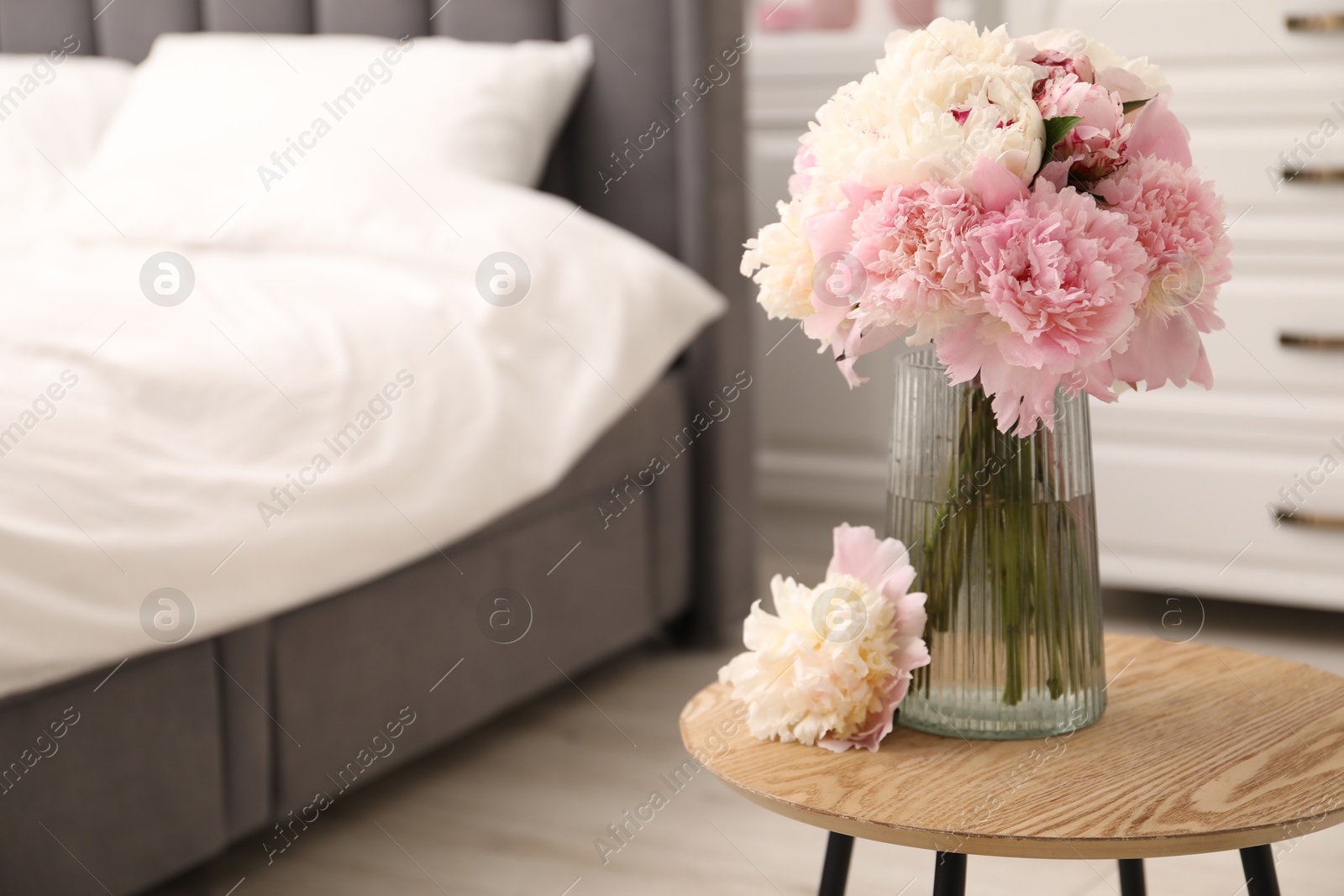 Beautiful peonies in vase on wooden table indoors. Space for text Photo of Beautiful peonies in vase on wooden table indoors. Space for text