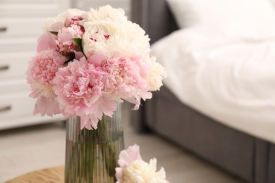 Photo of Beautiful peonies in vase on wooden table indoors, closeup. Space for text
