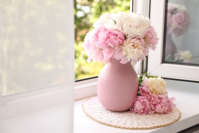 Photo of Beautiful peonies in vase on windowsill indoors