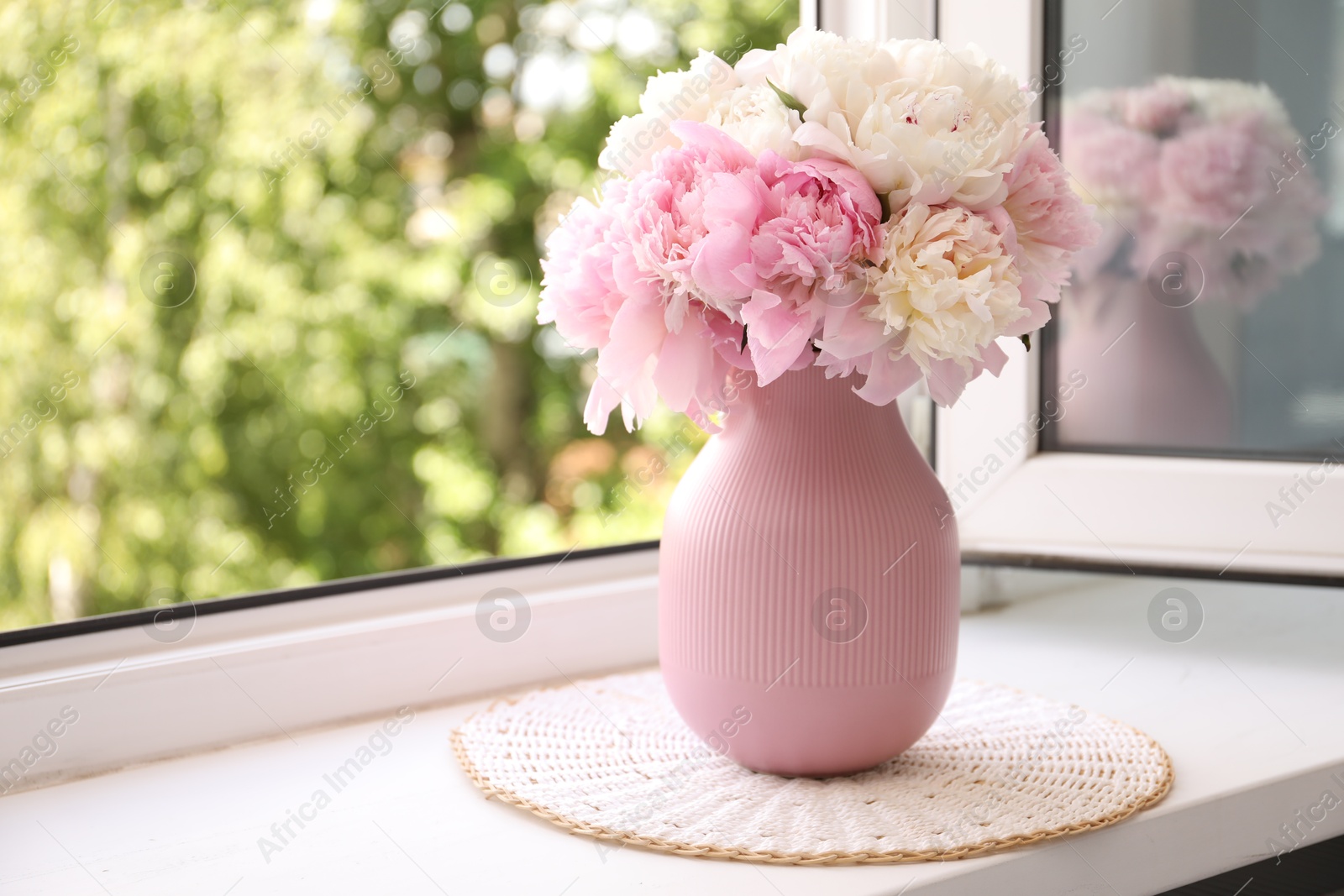Beautiful peonies in vase on windowsill indoors. Space for text Photo of Beautiful peonies in vase on windowsill indoors. Space for text
