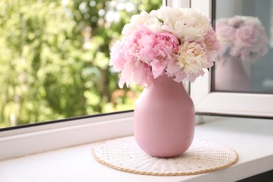 Photo of Beautiful peonies in vase on windowsill indoors. Space for text