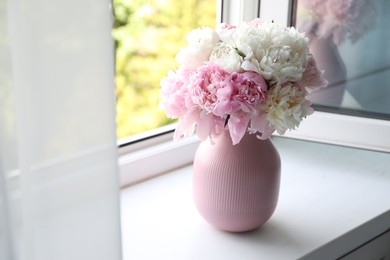 Photo of Beautiful peonies in vase on windowsill indoors