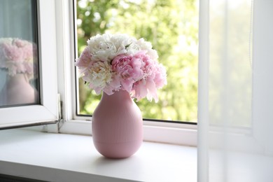 Photo of Beautiful peonies in vase on windowsill indoors