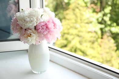 Photo of Beautiful peonies in vase on windowsill indoors. Space for text