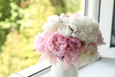 Photo of Beautiful peonies in vase on windowsill indoors, closeup