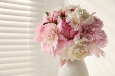 Photo of Bouquet of beautiful peonies in vase indoors, closeup. Space for text