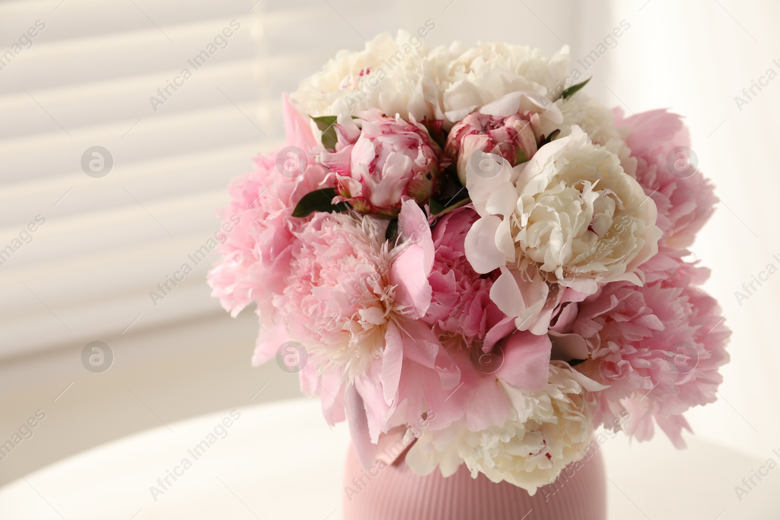 Bouquet of beautiful peonies in vase on white table indoors, closeup Photo of Bouquet of beautiful peonies in vase on white table indoors, closeup