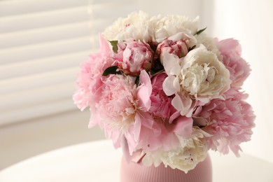 Photo of Bouquet of beautiful peonies in vase on white table indoors, closeup