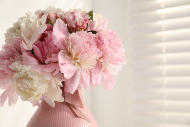 Photo of Bouquet of beautiful peonies in vase indoors, closeup. Space for text
