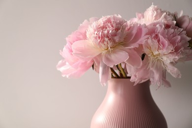 Photo of Bouquet of beautiful peonies on light grey background, closeup. Space for text