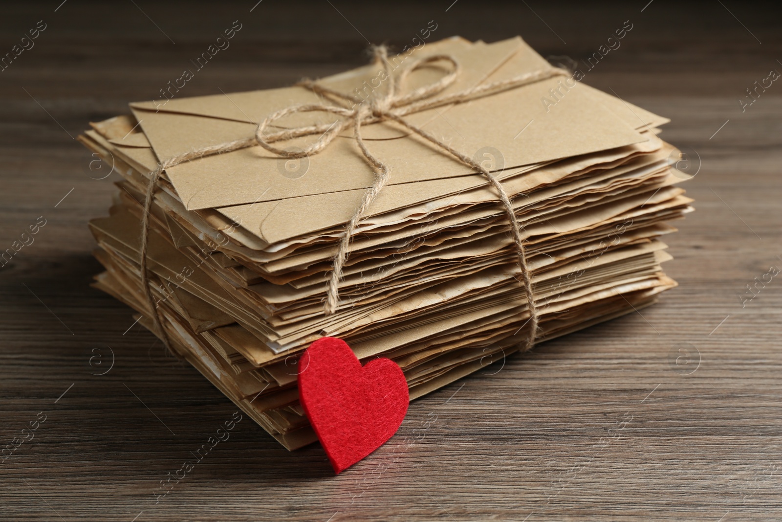 Stack of love letters and paper heart on wooden table, closeup Photo of Stack of love letters and paper heart on wooden table, closeup