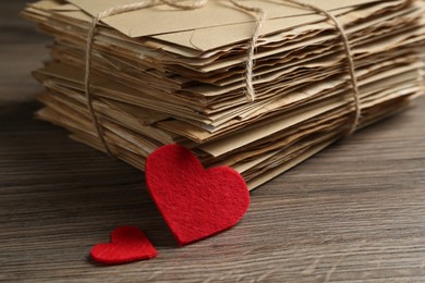 Photo of Stack of love letters and paper hearts on wooden table, closeup