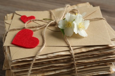 Photo of Stack of love letters, paper hearts and flowers on table, closeup