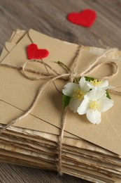 Photo of Stack of love letters, paper hearts and flowers on wooden table, closeup