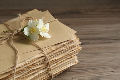 Photo of Stack of love letters and flowers on wooden table, closeup. Space for text