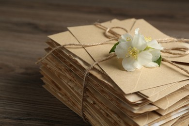 Photo of Stack of love letters and flowers on wooden table, closeup