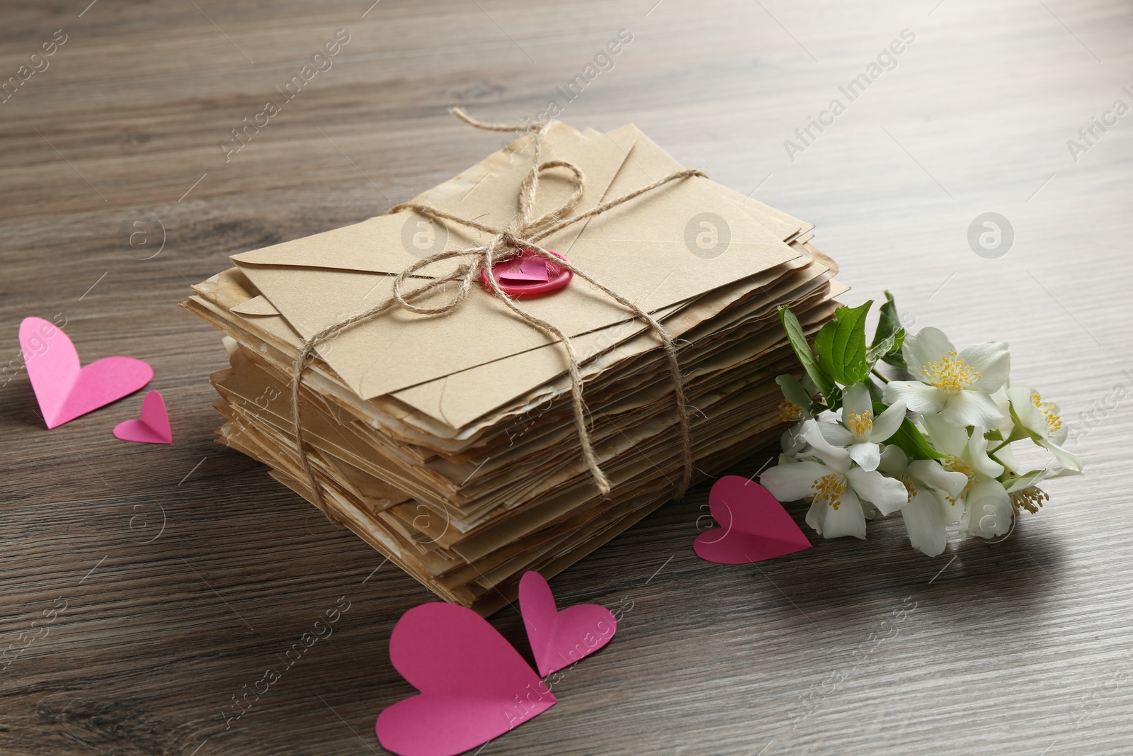 Stack of love letters, paper hearts and flowers on wooden table, closeup Photo of Stack of love letters, paper hearts and flowers on wooden table, closeup