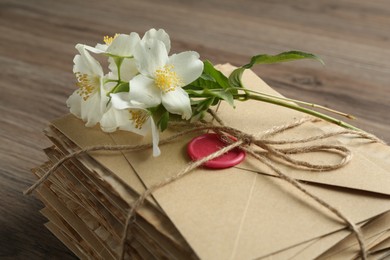 Photo of Stack of love letters and flowers on wooden table, closeup
